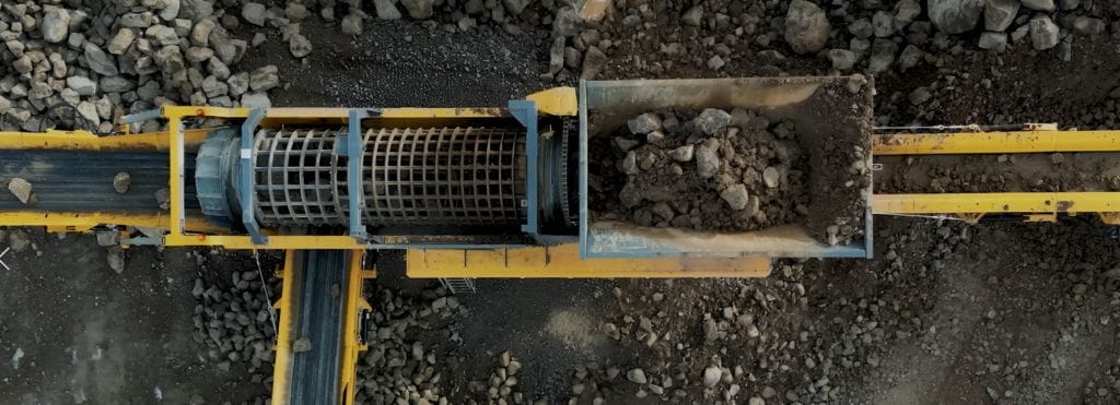 ranoworks Aerial view of industrial machinery, including screeners and conveyor belts, sorting and transporting rocks and soil at a mining or construction site.